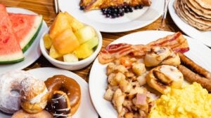 Several plates on a table full of breakfast food